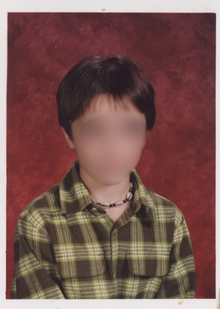 My 3rd grade picture day photo, I am a green plaid button up shirt on and a shell necklace. My hair is short.
